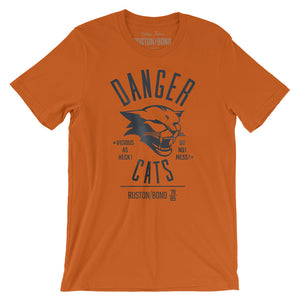 A retro bold, sarcastic graphic t-shirt in orange, featuring a mean cat image, with the words DANGER CATS, Vicious as heck—do not mess typography. From fashion brand Ruston/Bond, from wolfsaint.net