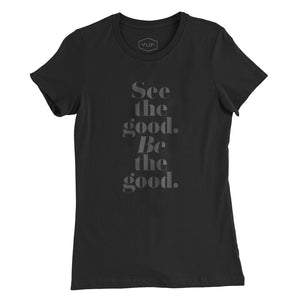 A women’s cut fashion t-shirt in Classic Black, with elegant typography in a vertical stack: “See the good. BE the good.” By fashion brand YUF, for wolfsaint.net