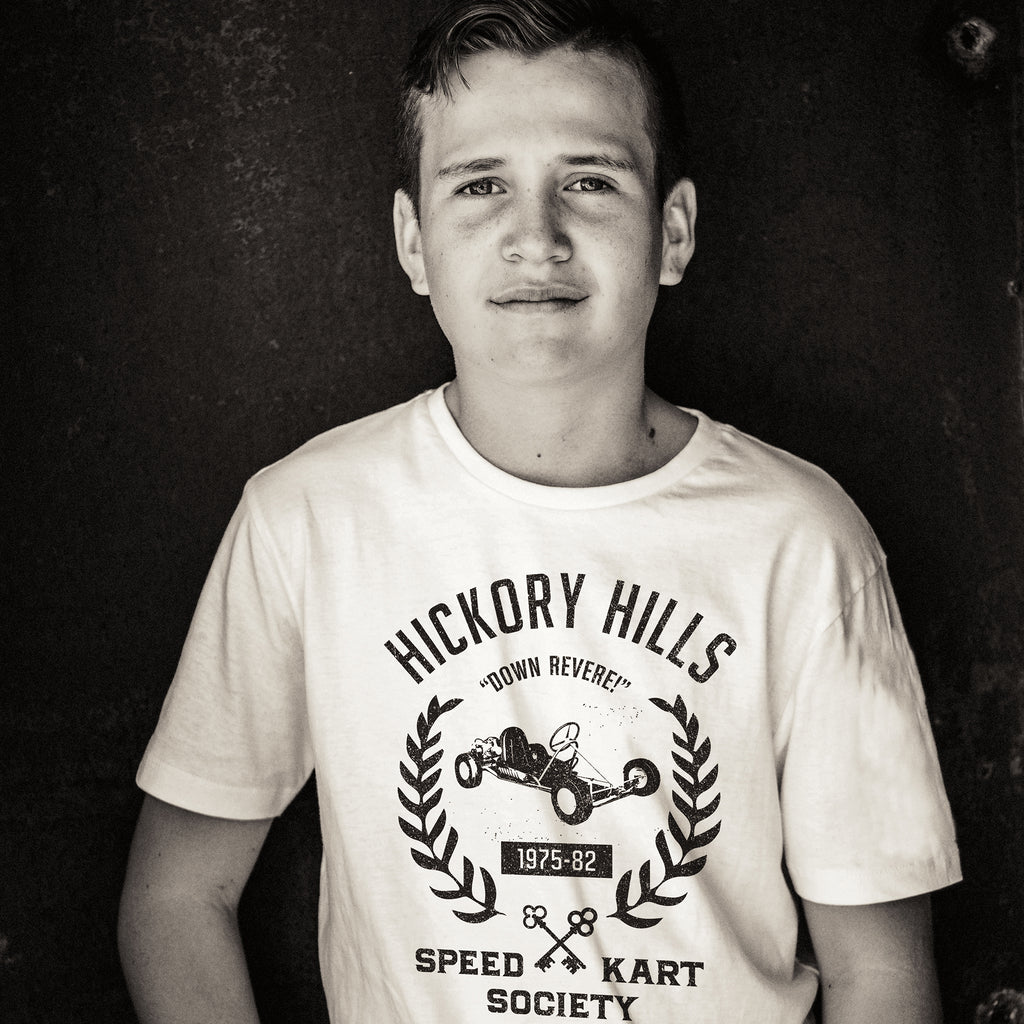 A young boy wears a ‘vintage fiction,’ retro t-shirt picturing a go-kart, promoting a small town racing league from 1975-1982 in Hockessin, Delaware. Inspired by the films of Wes Anderson. By fashion brand VNTG., from wolfsaint.net