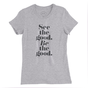 A women’s cut fashion t-shirt in Classic Heather Gray, with elegant typography in a vertical stack: “See the good. BE the good.” By fashion brand YUF, for wolfsaint.net