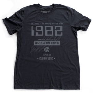 A vintage-inspired t-shirt in navy, featuring retro digital font reading “1982” with French taglines and a 45 record adapter graphic, promoting a fictional Monte Carlo discotheque from the 1970s and 80s. By fashion brand Ruston/Bond, from wolfsaint.net