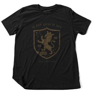 A retro, vintage-inspired fashion t-shirt in Classic Black, with an medieval graphic of a lion within a shield,surrounded by the sarcastic text in Latin “it is what it is,” and New York, Rio, Los Angeles at the bottom. By fashion brand Ruston/Bond, from wolfsaint.net