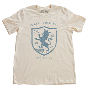 A retro, vintage-inspired fashion t-shirt in Soft Cream, with an medieval graphic of a lion within a shield,surrounded by the sarcastic text in Latin “it is what it is,” and New York, Rio, Los Angeles at the bottom. By fashion brand Ruston/Bond, from wolfsaint.net