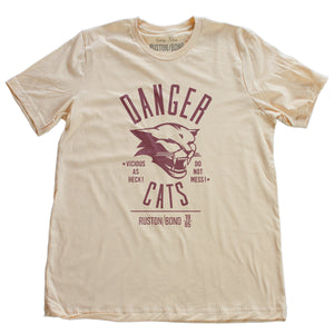 A retro bold, sarcastic graphic t-shirt in soft cream, featuring a mean cat image, with the words DANGER CATS, Vicious as heck—do not mess typography. From fashion brand Ruston/Bond, from wolfsaint.net