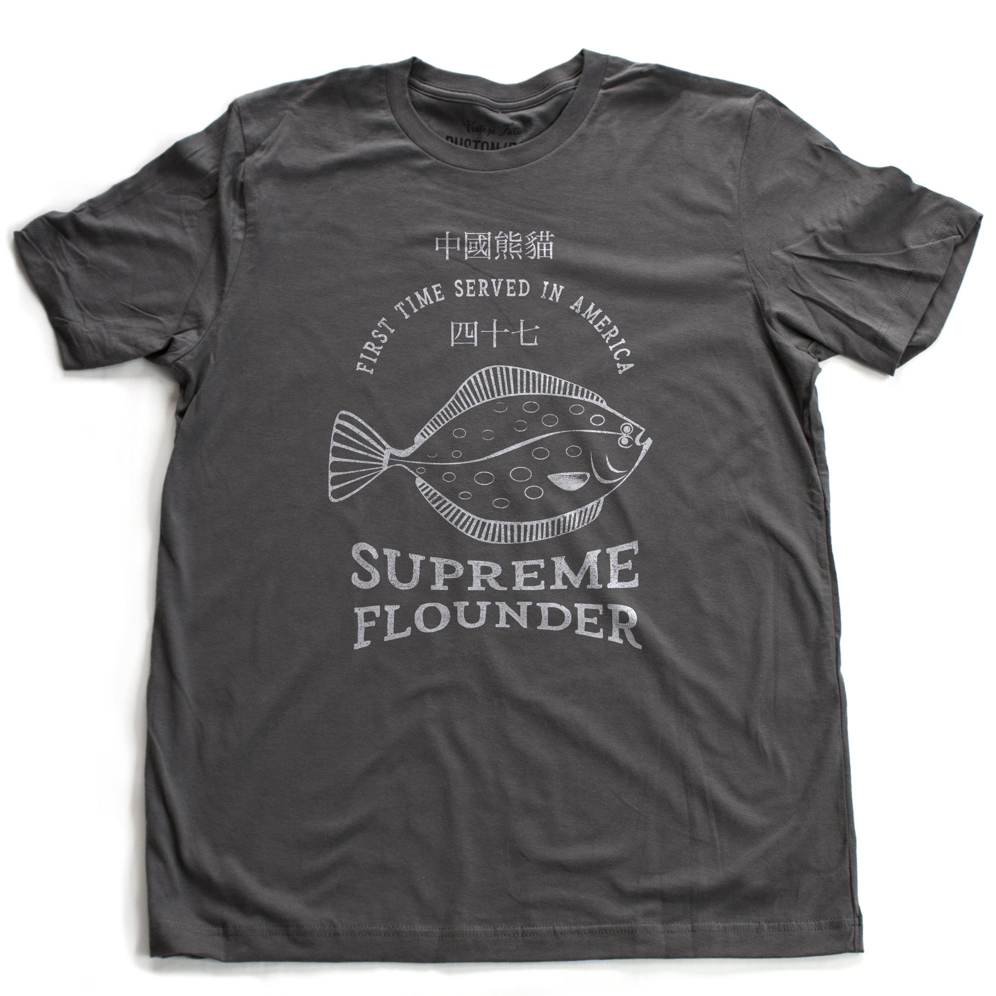 A fashionable retro design t-shirt, inspired by a Seinfeld tv episode, and Julia Louis-Dreyfus’ Elaine Benes’ character’s favorite Chinese food dish. The graphic is a fish, with the words SUPREME FLOUNDER, First Time Served in America, and Chinese characters. From fashion brand RUSTON/BOND for wolfsaint.net