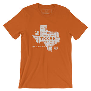 A stylish graphic t-shirt featuring the form of the state of Texas, with the various most populous Texan cities arranged as a collage within the state shape. It also commemorates the year 1845 and state motto “friendship.” By Wolfsaint.net