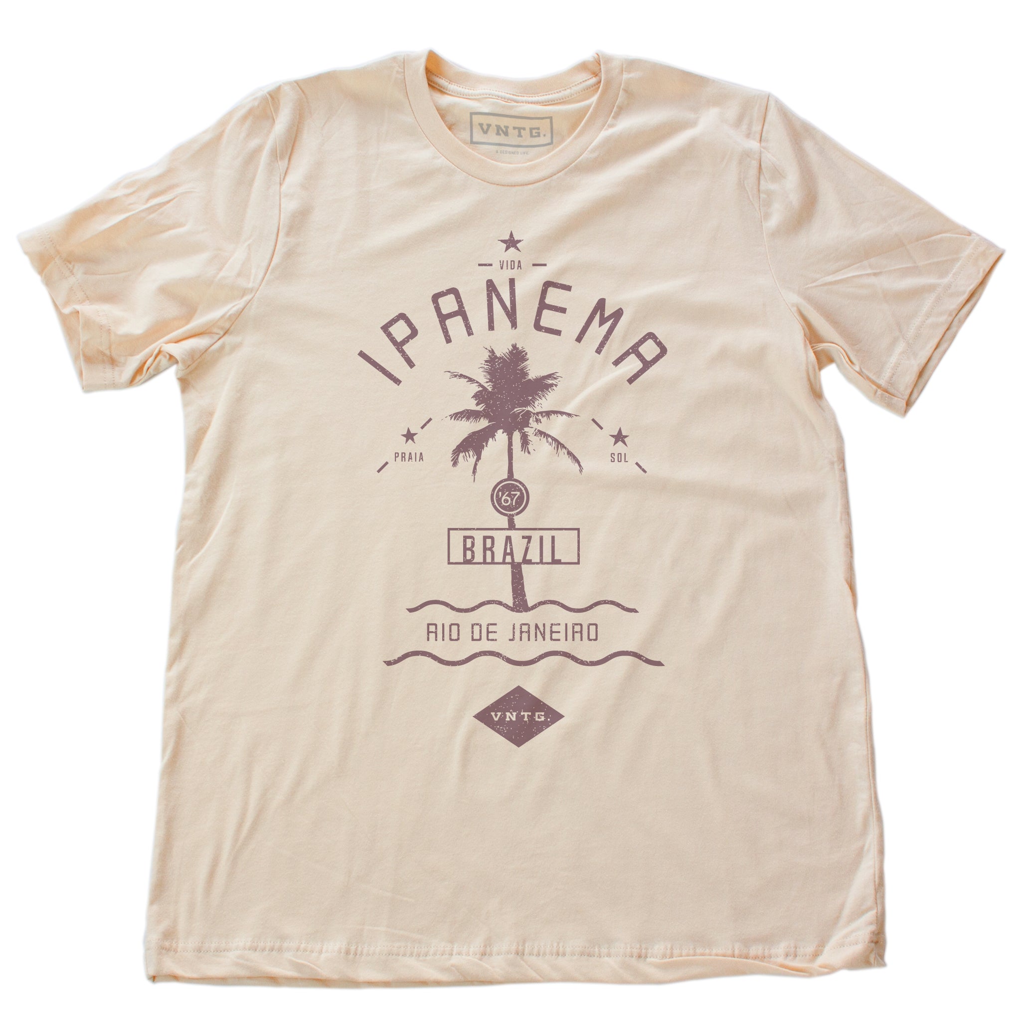 A vintage-inspired, Classic retro t-shirt in Soft Cream, featuring a graphic of a single palm tree over waves, as a tourism promotion for Ipanema beach, in Rio de Janeiro, Brazil. By fashion brand VNTG., from Wolfsaint.net