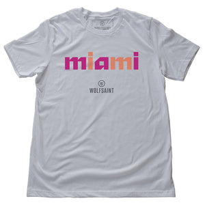 A stylish fashion-shirt in white, with a colorful graphic modern typographic treatment of “miami” in pink and orange lowercase letters, with the Wolfsaint logo beneath it. From wolfsaint.net
