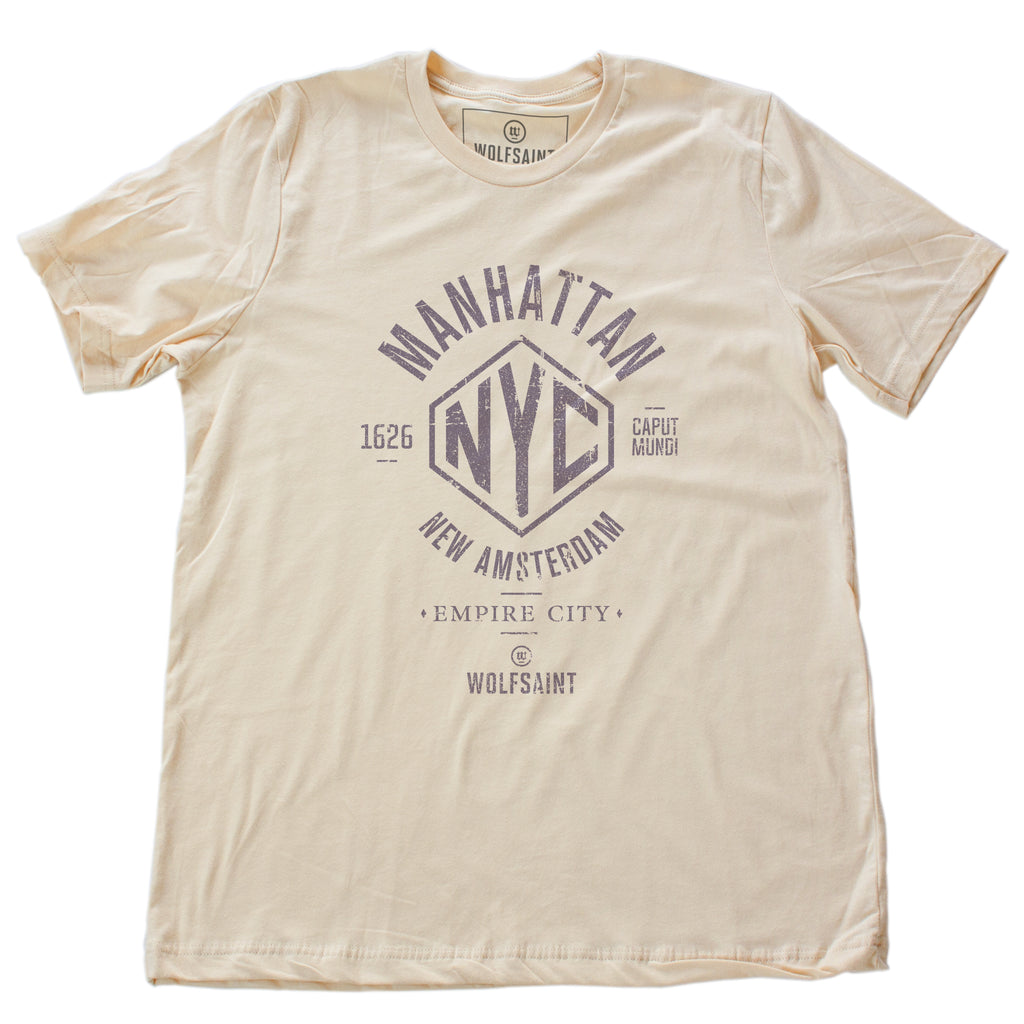 A vintage-inspired retro designed fashion-shirt in Soft Cream, featuring an “NYC” graphic surrounded by the words “Manhattan” and “New Amsterdam / Empire City” and the year of its founding, 1626, along with the Latin words Caput Mundi, meaning Capital of the World. From wolfsaint.net