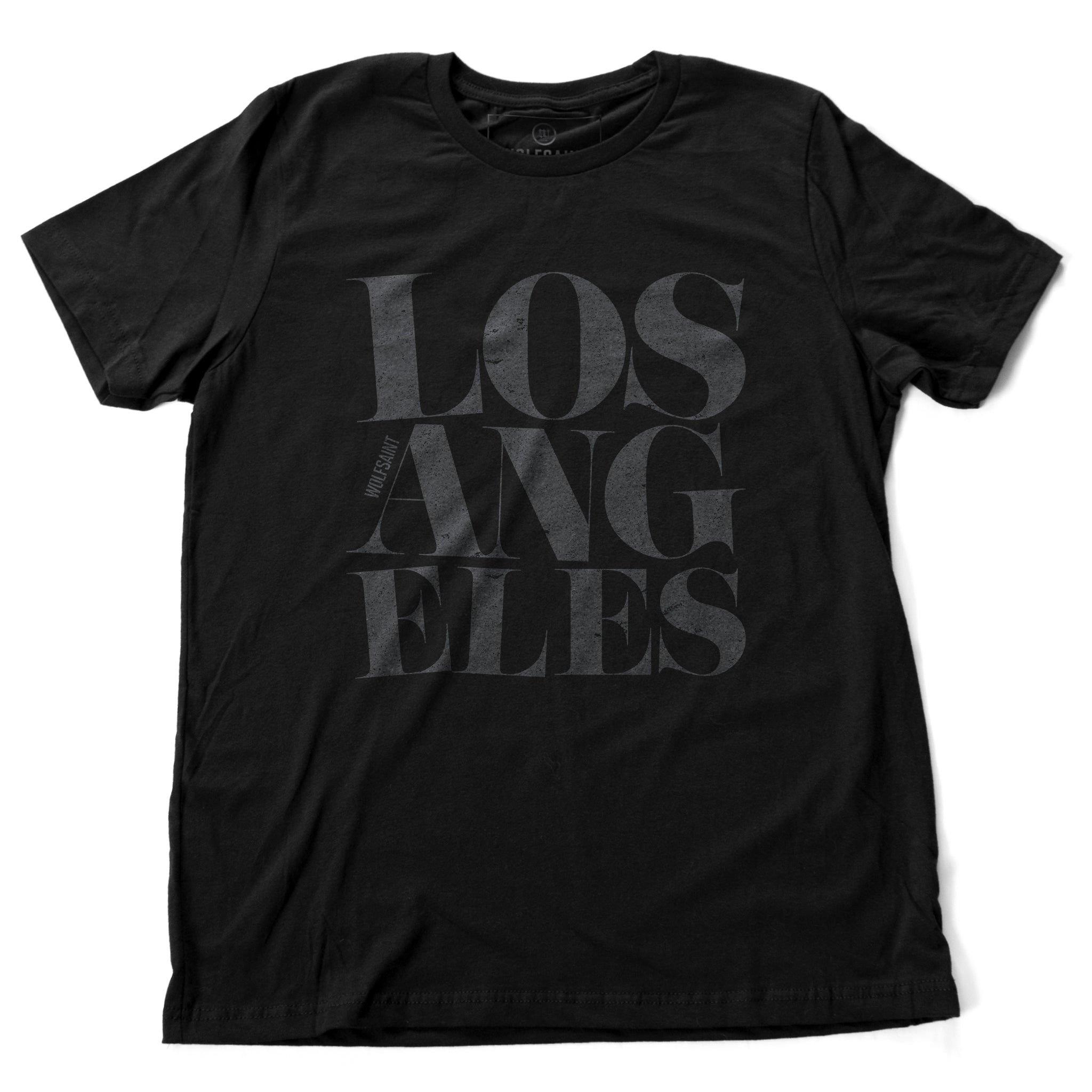 A fashionable black graphic t-shirt featuring the word “LOS ANGELES” in a elegant font, stacked in three tilted lines to sarcastically simulate an earthquake. From wolfsaint.net