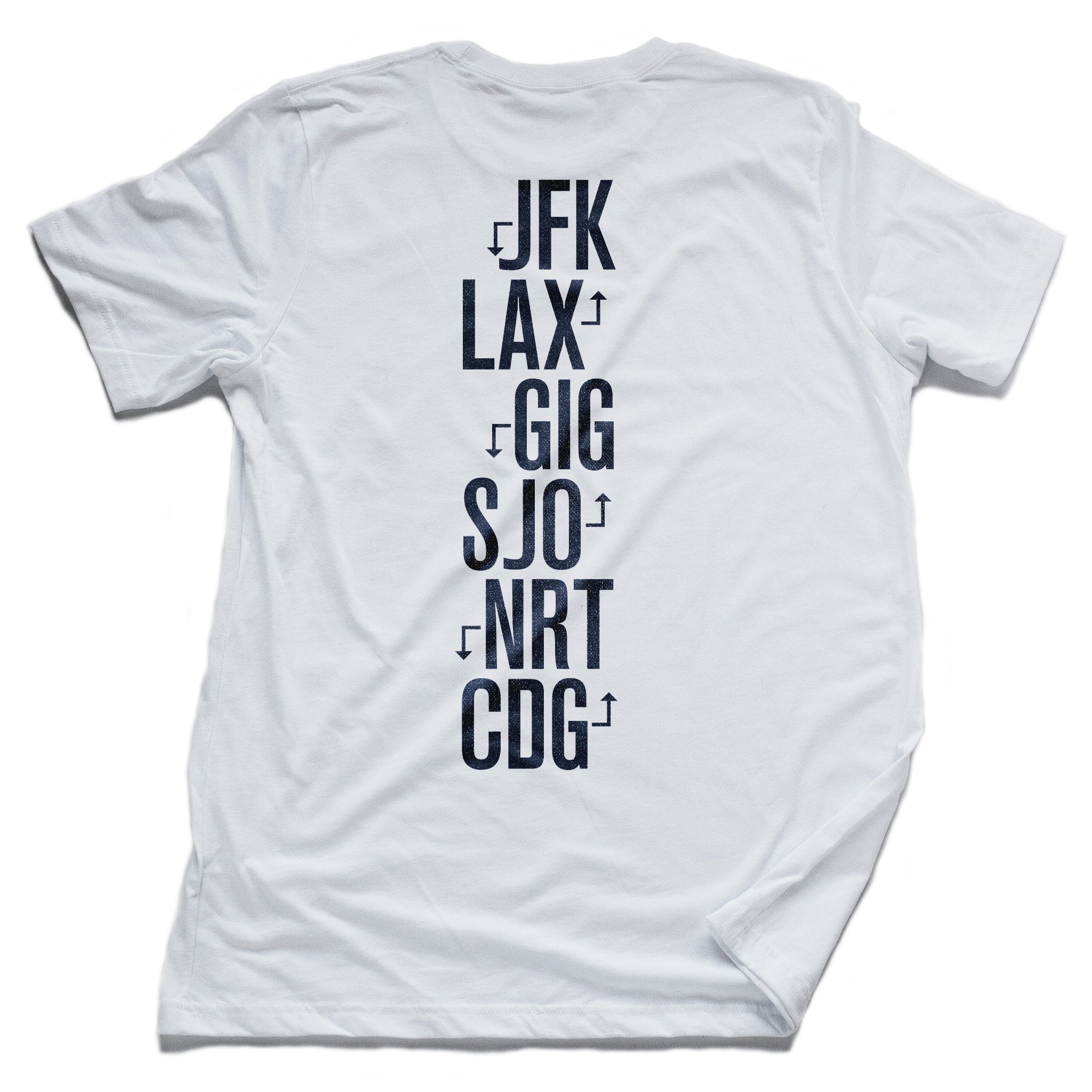 The back of the white version of a fashion t-shirt representing a jetsetting lifestyle. On the front of the shirts is a simple graphic of a commercial airliner superimposed on a globe, and the word “Worldwide.” On the reverse is a stack of airport codes representing international travel (New York/JFK, Los Angeles/LAX; Rio de Janeiro/GIG; San Jose Costa Rica/SJO; Tokyo/NRT; Paris/CDG). By fashion brand WOLFSAINT, from wolfsaint.net