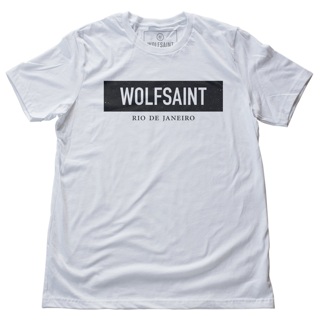 A simple fashion-branded white t-shirt with the WOLFSAINT gothic logo in a black rectangle, and “Rio de Janeiro” in smaller type below. From Wolfsaint.net