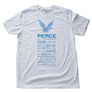 A classic retro graphic t-shirt in White featuring a dove above the word “PEACE.” Below, are the words for Peace in multiple languages from around the world. By fashion brand Wolfsaint, available at wolfsaint.net