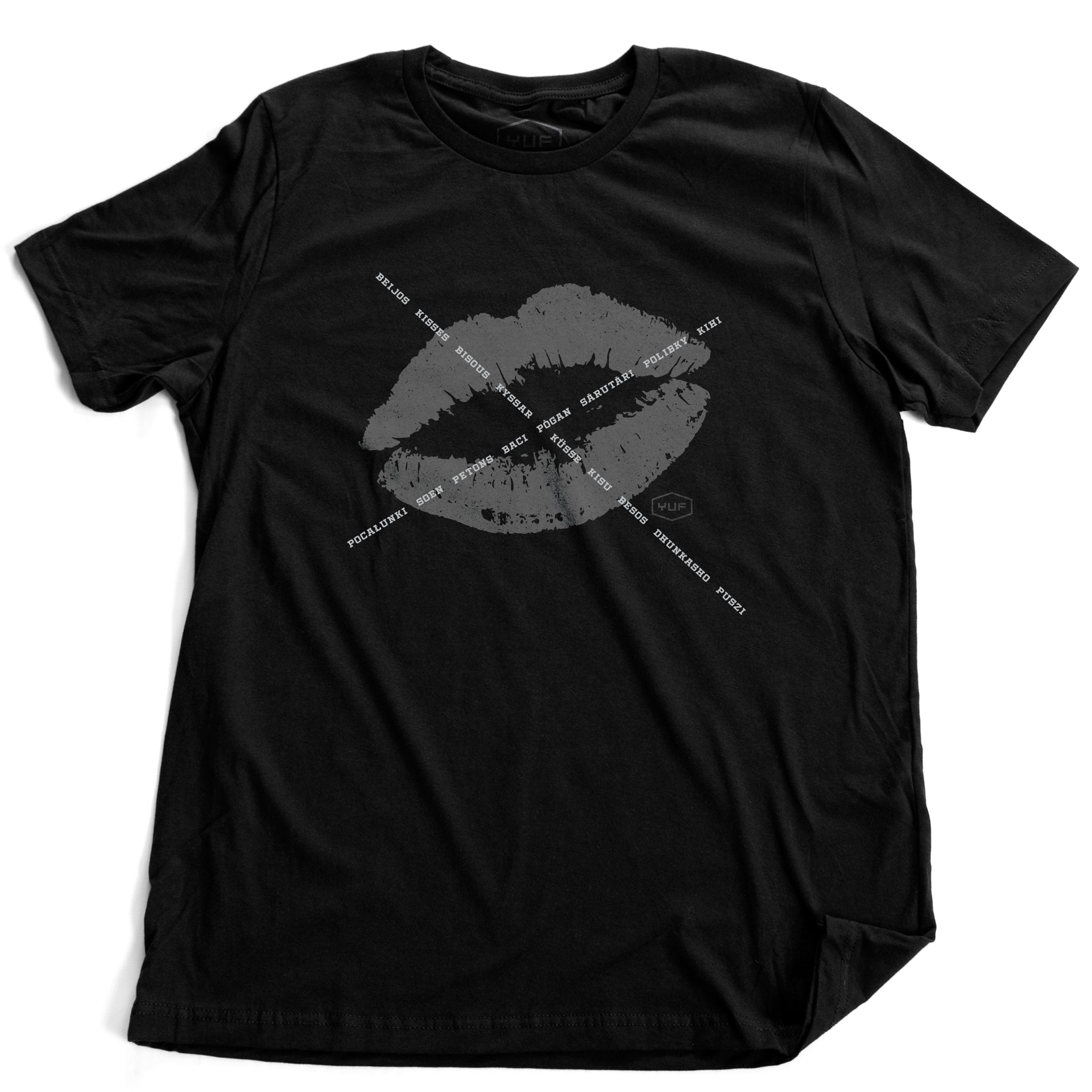 A unisex fashion t-shirt in black, featuring a lipstick kiss graphic, criss-crossed by the word for “kiss” in various languages. A classic icon reminiscent of Marilyn Monroe’s signature mark. By fashion brand YUF, from wolfsaint.net