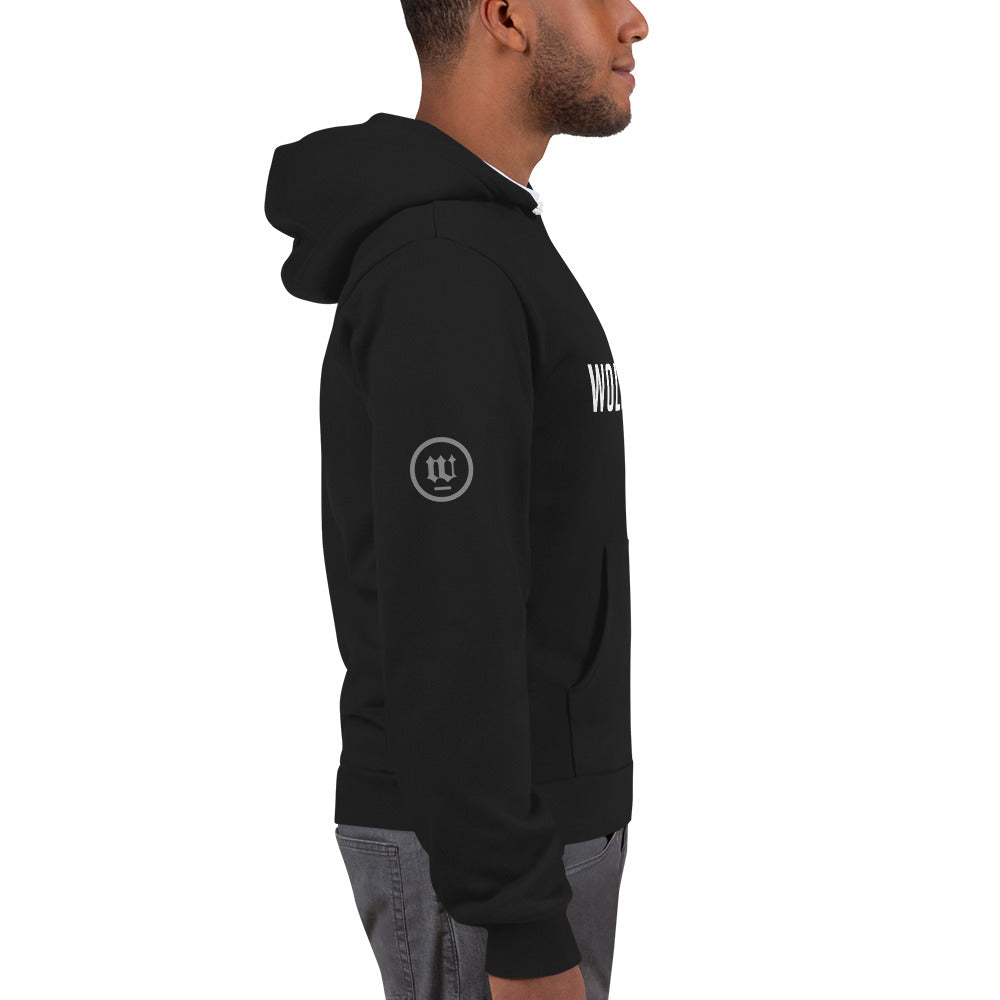 A male model in a white studio wearing a fashionable, trendy black zippered hoodie sweatshirt with the WOLFSAINT gothic logo in white across the chest and the “W” circle crest on the right sleeve. From fashion brand wolfsaint.net
