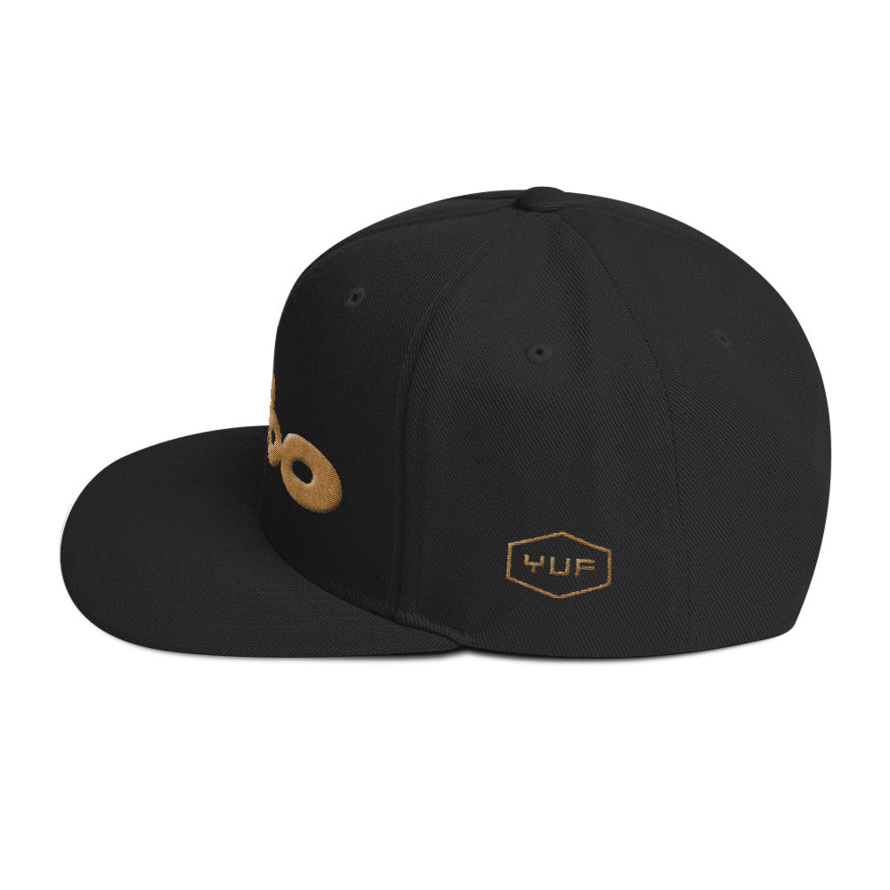 Side view of a black retro, classic snapback baseball cap with the sarcastic/ironic word BIMBO embroidered in a streetwise bubble / graffiti font for skateboarders, rappers, athletes, etc.