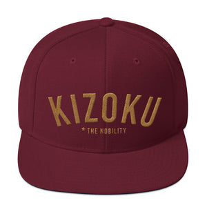 A classic SnapBack cap in Maroon, with the Japanese word “KIZOKU” in raised gold embroidery, representing “The Nobility” —by fashion brand WOLFSAINT, from wolfsaint.net