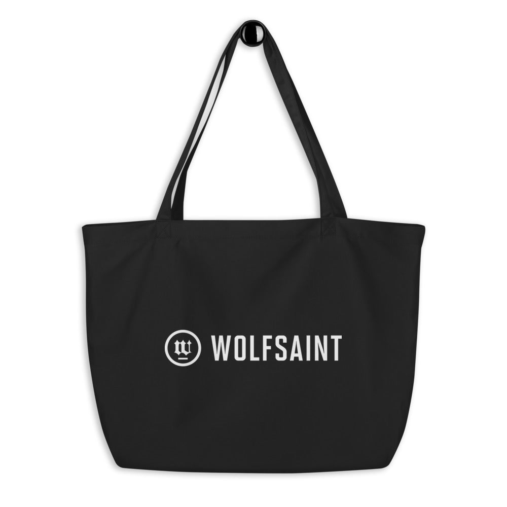 A large simple beach or city tote bag in black, with the WOLFSAINT gothic logo and crest printed in warm white. From Wolfsaint.net