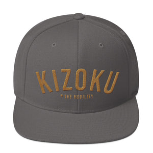 A classic SnapBack cap in Gray, with the Japanese word “KIZOKU” in raised gold embroidery, representing “The Nobility” —by fashion brand WOLFSAINT, from wolfsaint.net
