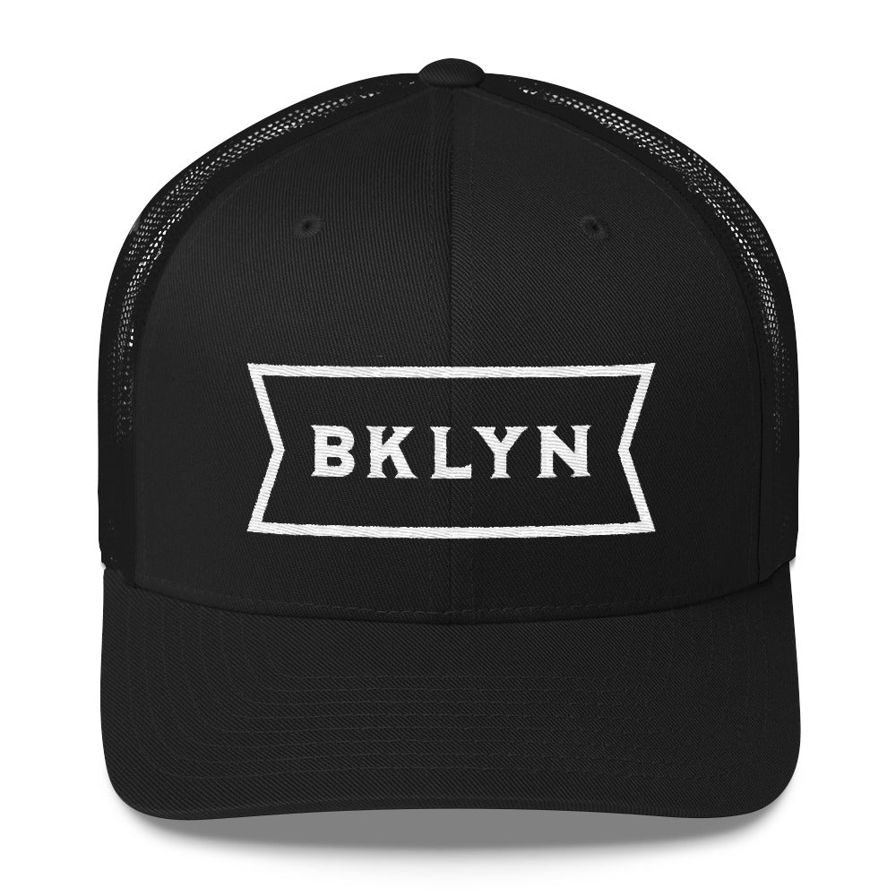 Black on black, mesh back classic trucker’s cap, with a strong vintage abbreviated BROOKLYN typographic graphic. From wolfsaint.net 