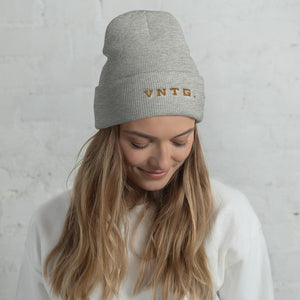 A smiling young woman wearing a stylish knit cap, with the brand logo VNTG. embroidered in gold thread. From wolfsaint.net